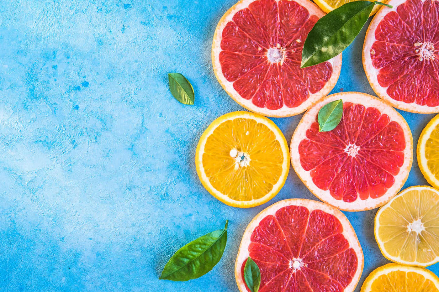 Sliced grapefruits and lemons on a blue background