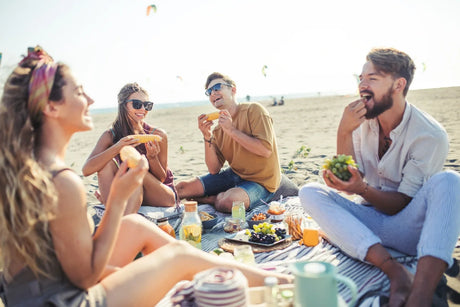 Group of friends enjoying a picnic on a sandy beach.