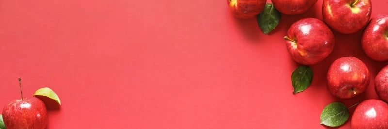 Red apples with green leaves on a red background