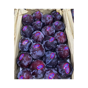 Fresh black plums, whole ripe stone fruit packed per box isolated on white background